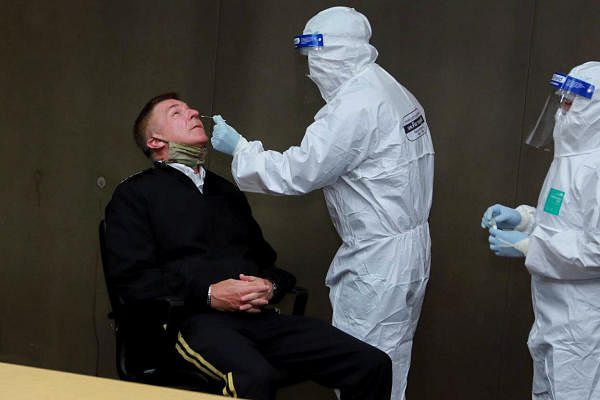 A health officer wearing personal protective equipment (PPE) performs a nose swab test on U.S. Army Chief of Staff General James C. McConville at a military airport in Bangkok, Thailand. Credit: Reuters Photo