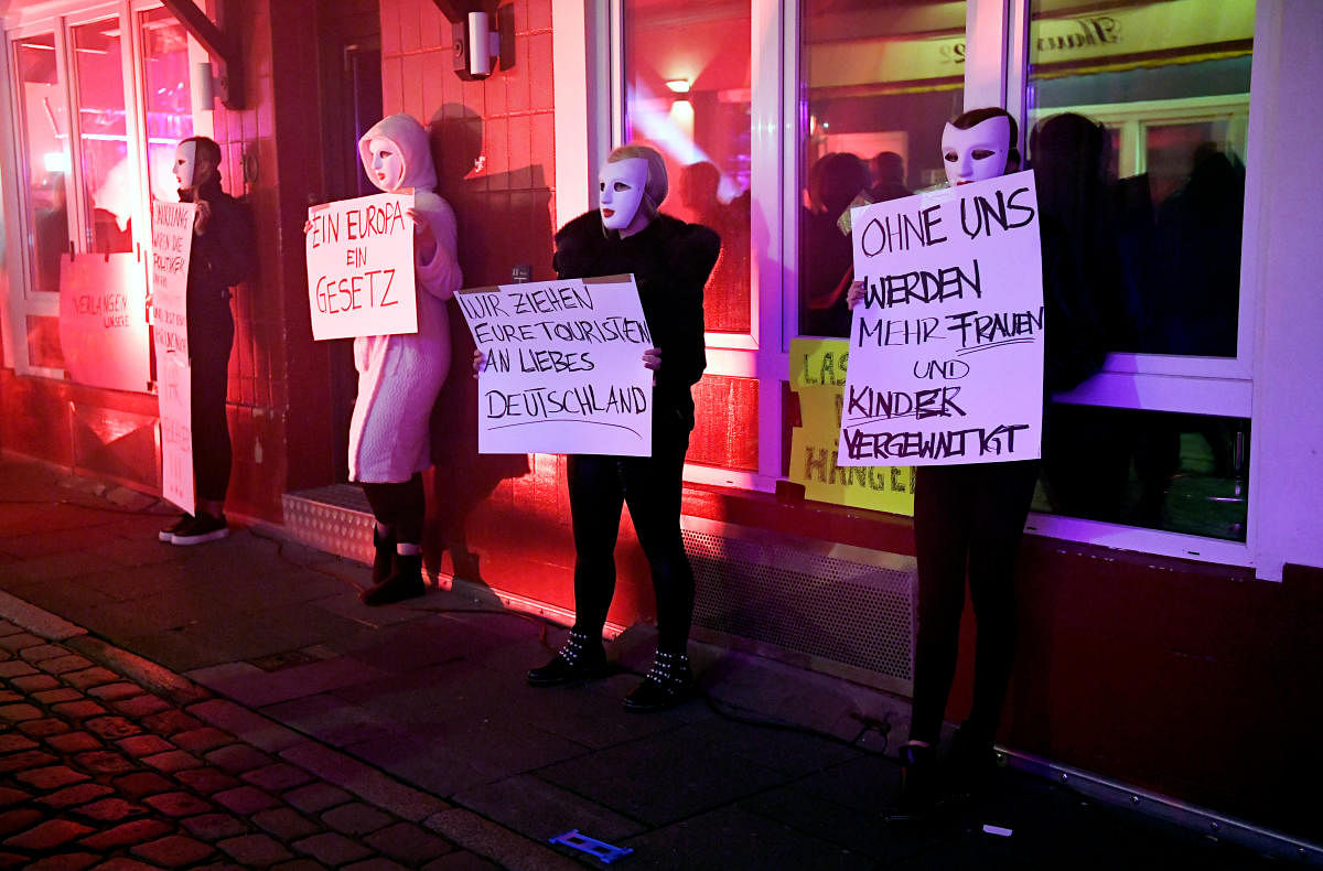 Prostitutes wearing masks hold signs reading "One Europe - One Law", "We attract your tourists, dear Germany" and "Without us more women and children will be violated", during a rally of prostitutes demanding the reopening of Germany's brothels, amid the the spread of the coronavirus disease (COVID-19), in the famous red light district Reeperbahn in Hamburg, Germany July 11, 2020. Credit: REUTERS
