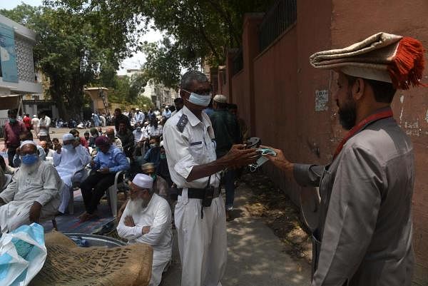 A traffic police officer distributes a face mask to a Muslim worshipper (R) as a preventive measure against the spread of the Covid-19. Credit: AFP