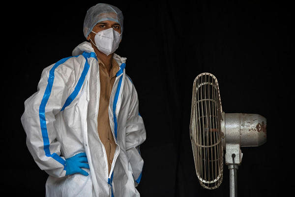 A health worker in personal protective equipment (PPE) takes a break while waiting for people to collect samples to conduct tests for the coronavirus disease (COVID-19), amid the spread of the disease, in New Delhi, India July 10, 2020. Credit: Reuters