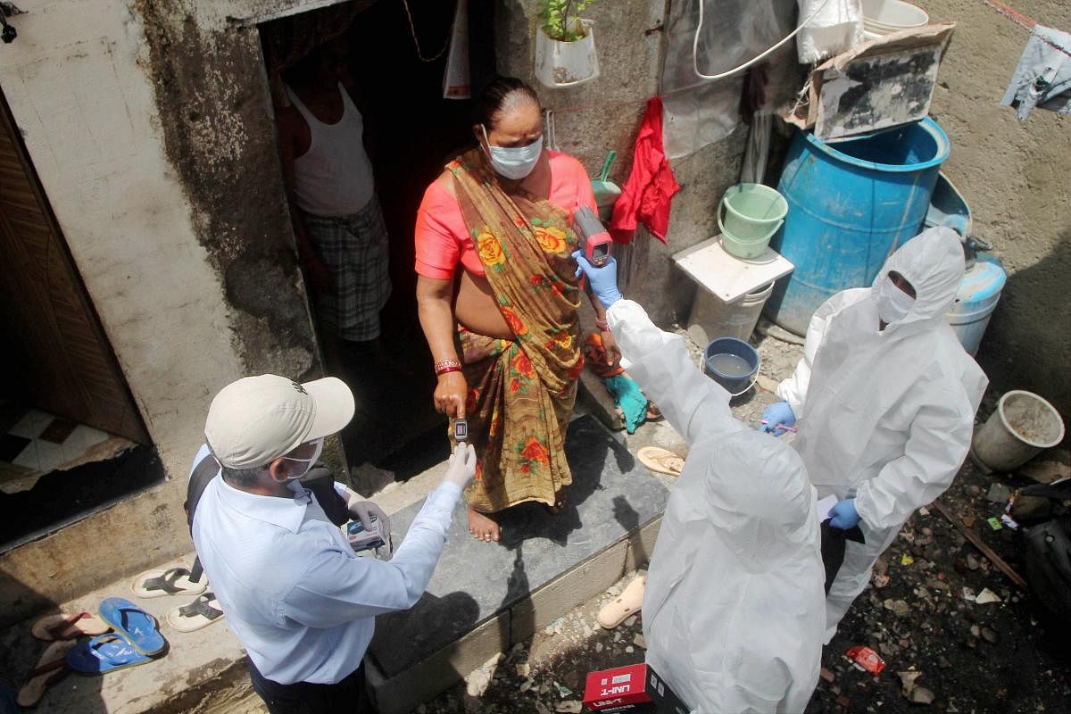 Health workers wearing PPE suits conduct screening of a woman resident in a Covid-19 containment zone in Ambujwadi area, in Mumbai (PTI Photo)