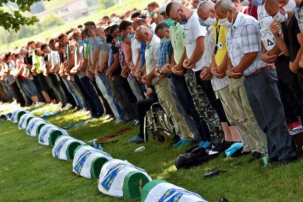 Bosnian Muslim men wearing face masks pray during a burial ceremony marking the 25th anniversary of the Srebrenica massacre, at the Potocari memorial cemetery, a village just outside Srebrenica. Credit: AFP Photo