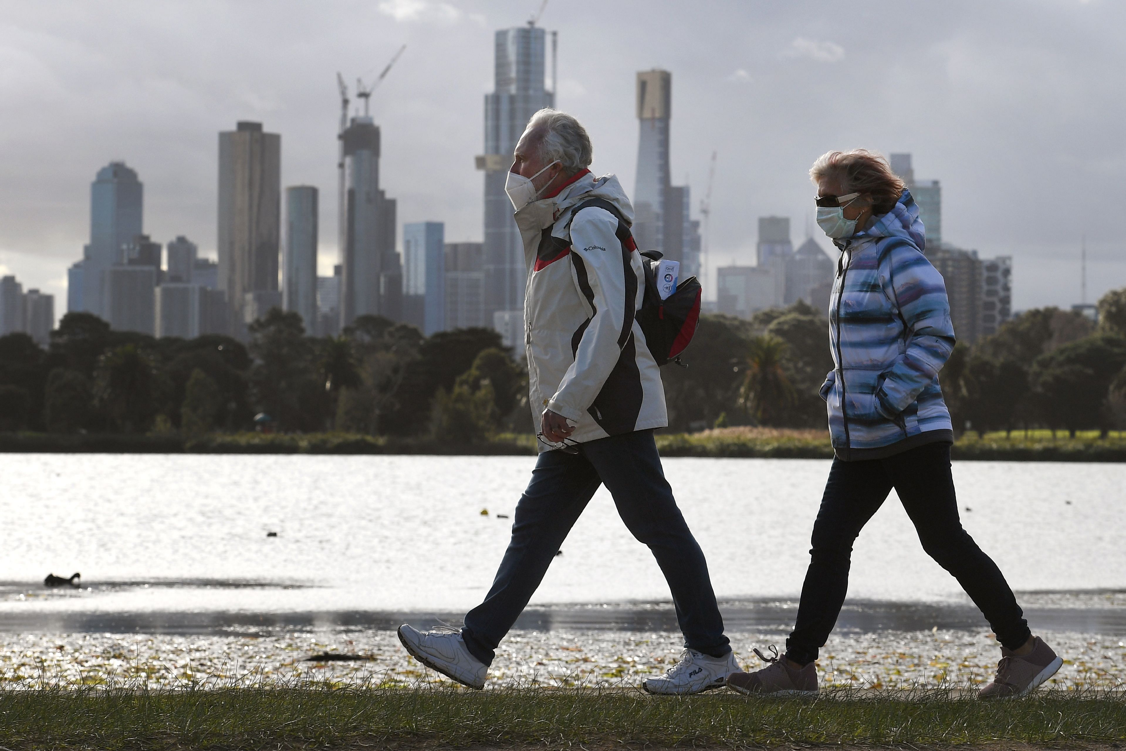 People walk along Albert Park lake in Melbourne on July 13, 2020, as five million people in Australia's second-biggest city began a new lockdown following a resurgence of coronavirus cases. (Photo by AFP)