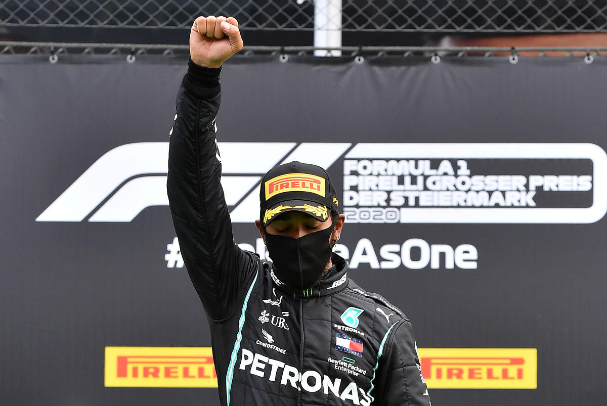 Mercedes' Lewis Hamilton wears a protective face mask as he celebrates winning the race on the podium with the trophy, following the resumption of F1 after the outbreak of the coronavirus disease. Credit: Reuters Photo