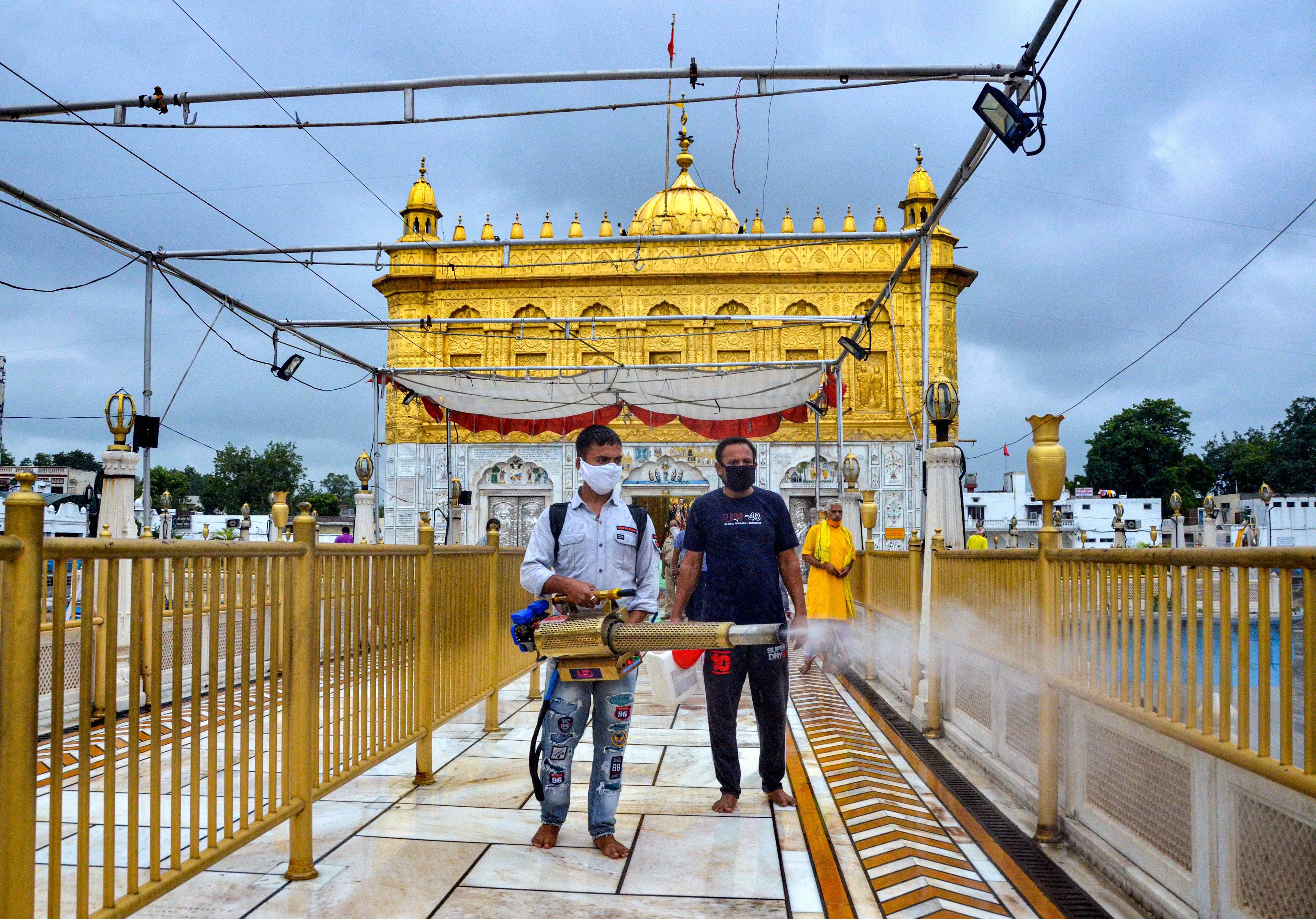 A worker sanitizes Durgiana Temple premises during the complete lockdown on weekend imposed by the state government as a preventive measure against the coronavirus, in Amritsar, Sunday, July 12, 2020. (PTI Photo)