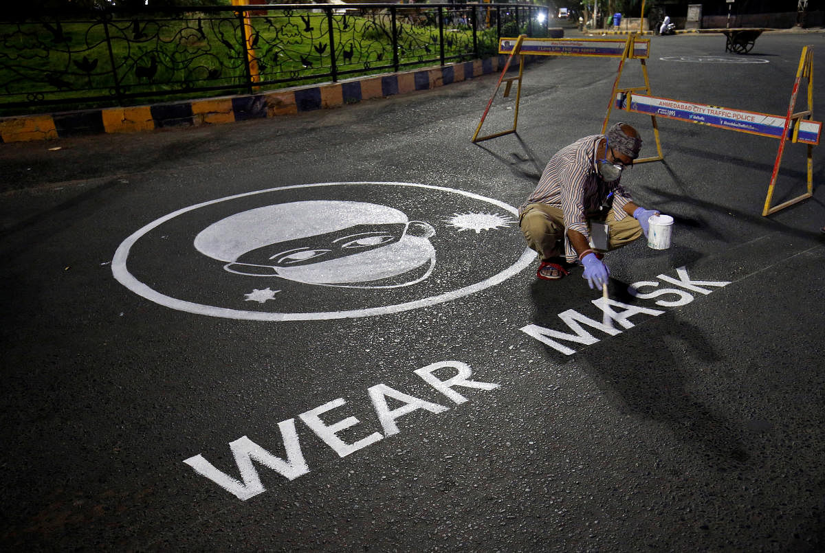 A man draws an awareness message on a road about wearing mask amid concerns about the spreading of coronavirus disease (Covid-19) in Ahmedabad, India. File Photo Credit: Reuters Photo 