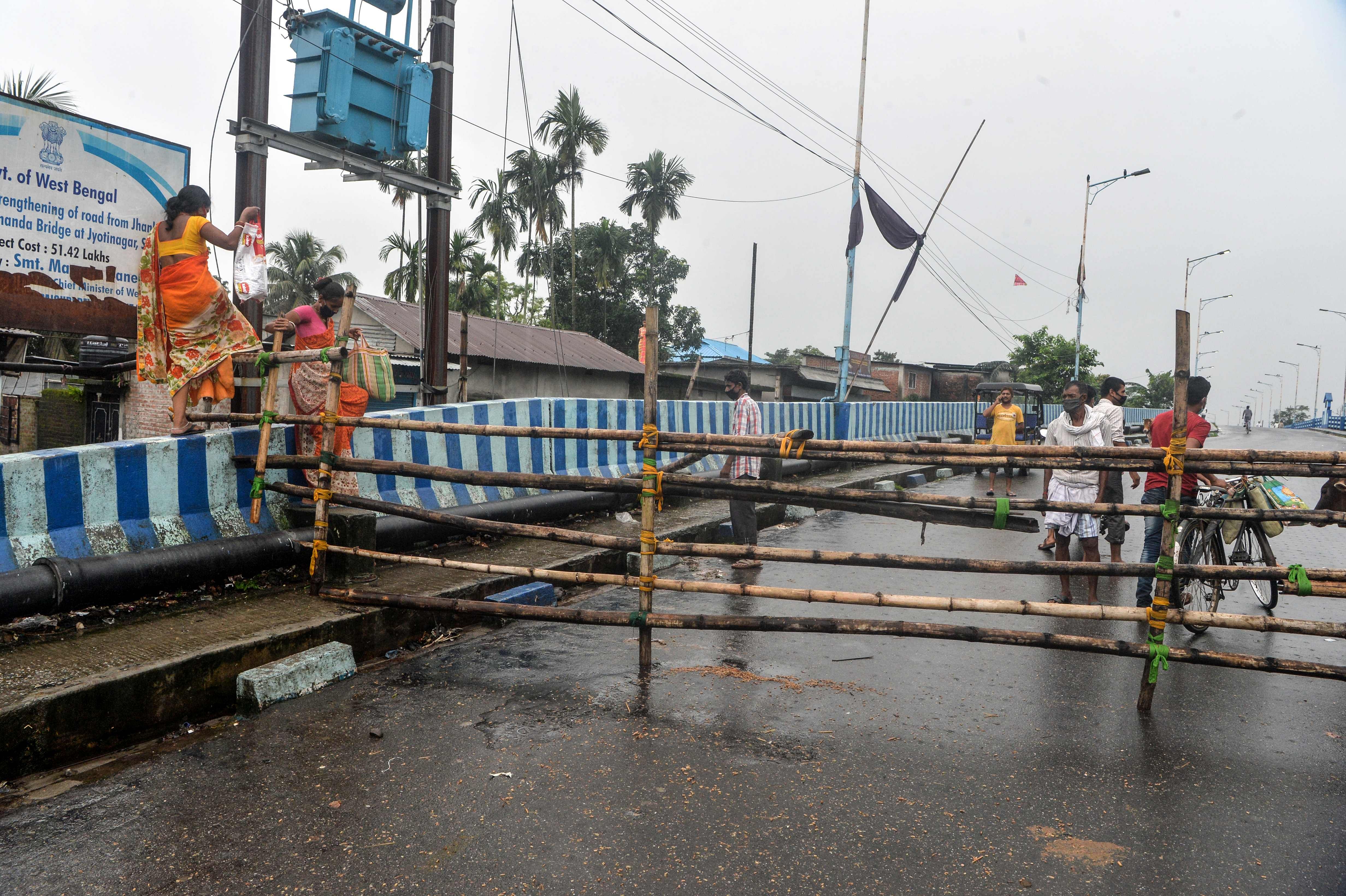 Residents climb barricades on a street shut after a recent lockdown was reimposed in nine wards under Siliguri Municipal area. Credit: AFP Photo