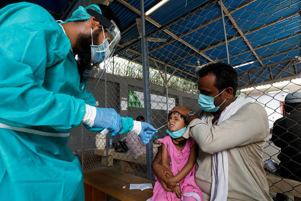 A paramedic wearing protective gear takes a nasal swab from a child, to be tested for the coronavirus in Karachi. Credit: Reuters