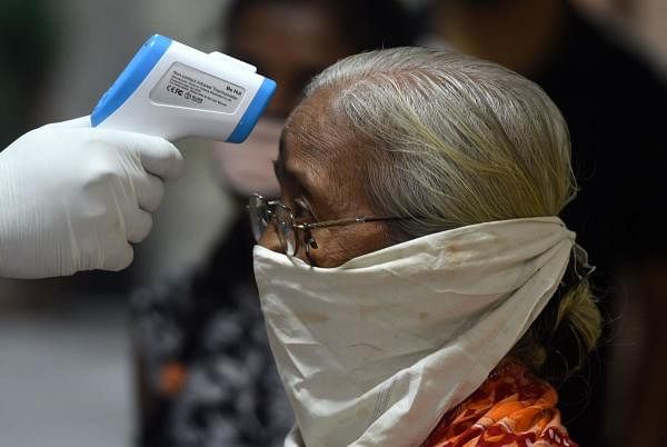 A medical volunteer takes temperature reading of a woman during a medical screening for the Covid-19. Credit: AFP