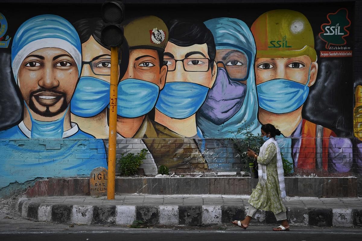 A woman walks past a mural of frontline workers after the government eased a nationwide lockdown imposed as a preventive measure against the Covid-19 coronavirus in New Delhi. Credit: AFP Photo