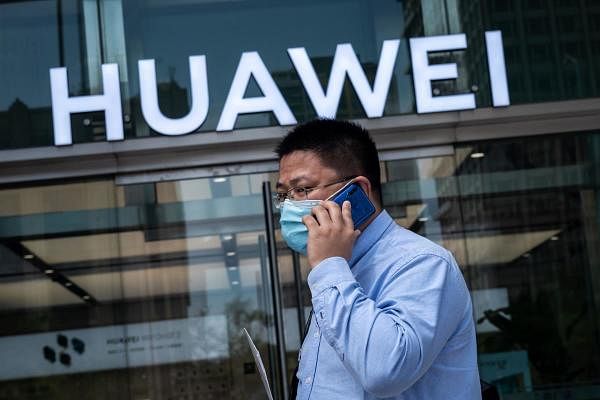 A man walks past a shop for Chinese telecoms giant Huawei in Beijing. Credit: AFP