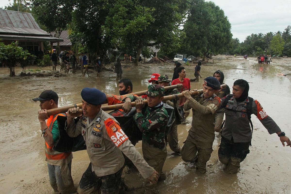 A rescue team carry a victim's body following flash flooding in Radda village in North Luwu regency, South Sulawesi on after three rivers overflowed due to torrential rains. Credit: AFP Photo: 