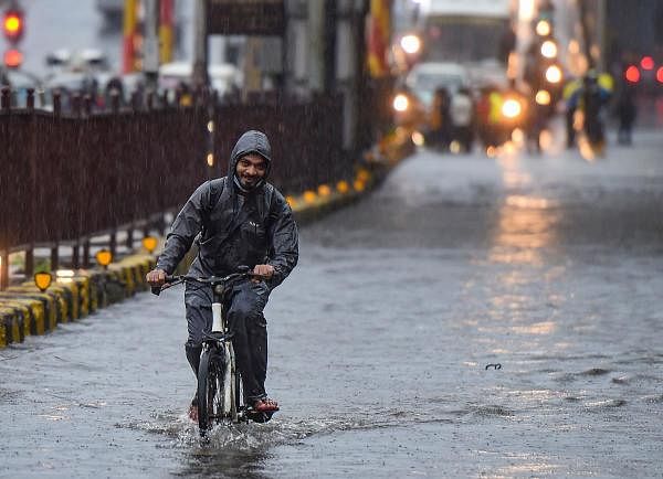 A youngster rides a bicycle on a waterlogged street, during monsoon rain, at Sion in Mumbai, Tuesday, July 14, 2020. Credit: PTI Photo