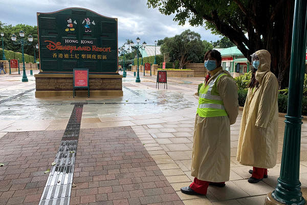 Employees wearing protective masks stand outside the Hong Kong Disneyland theme park that has been closed again. Credit: Reuters Photo