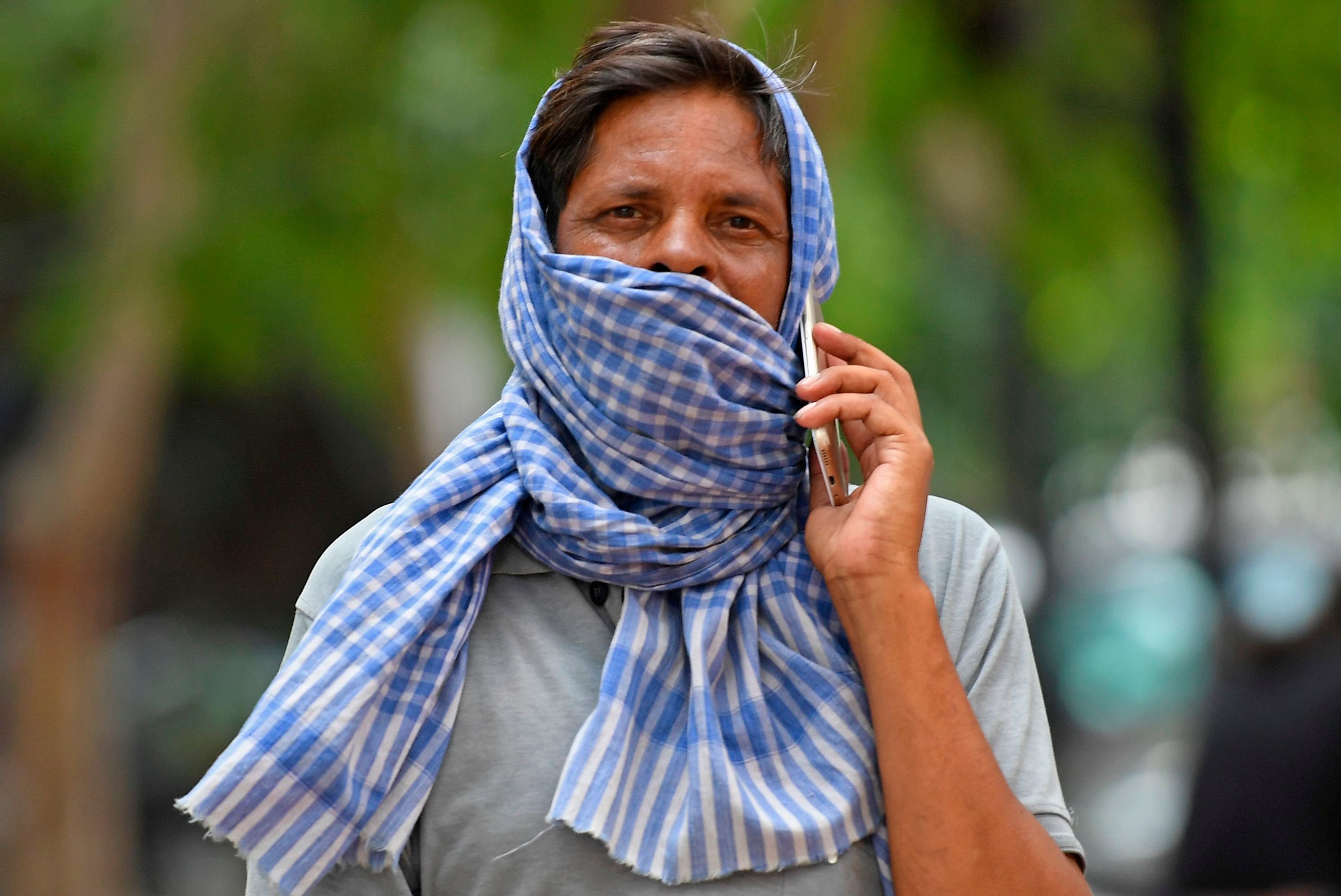 In this picture taken on July 10, 2020, a man speaks on a mobile phone while wearing a scarf over his mouth as a facemask during the novel coronavirus pandemic, in New Delhi. Credit: AFP Photo