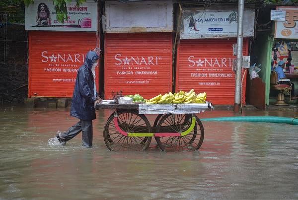 A vendor pushes his cart on a waterlogged street following heavy rainfall, in Mumbai. Credit: PTI