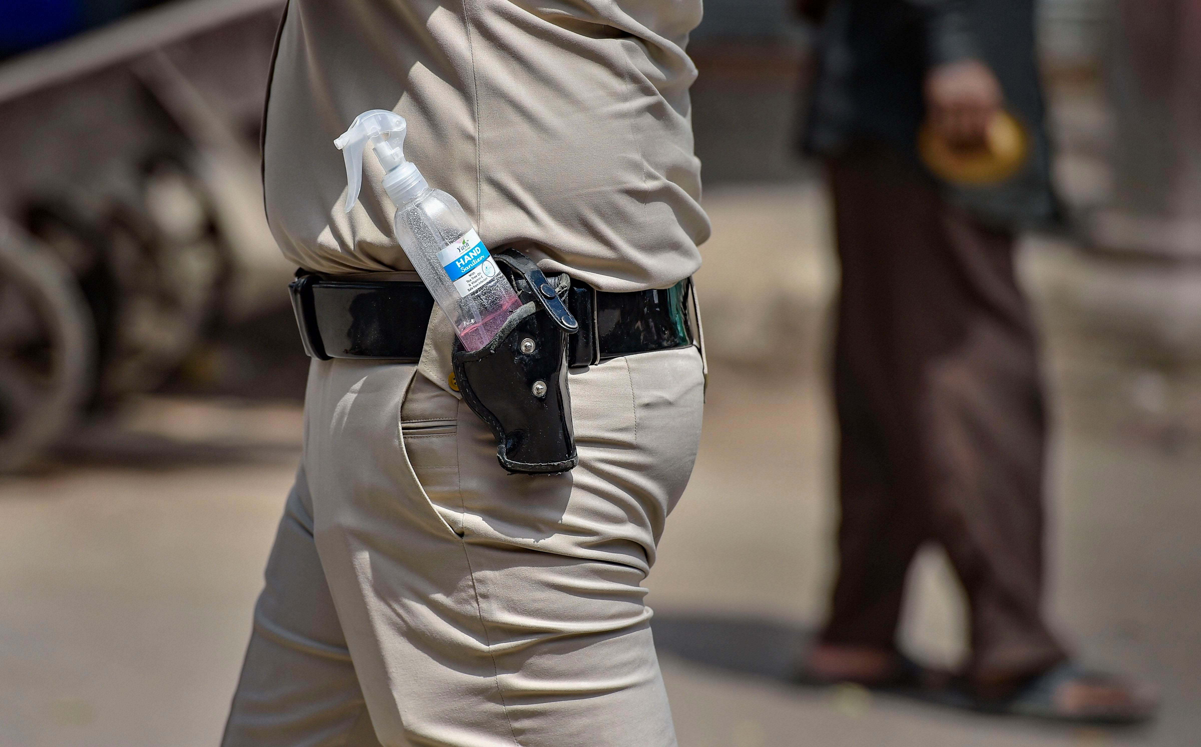  A policeman with a hand sanitiser in his gun belt manages proceedings as homeless people stand in a queue for food, during a nationwide lockdown. Credit: PTI Photo
