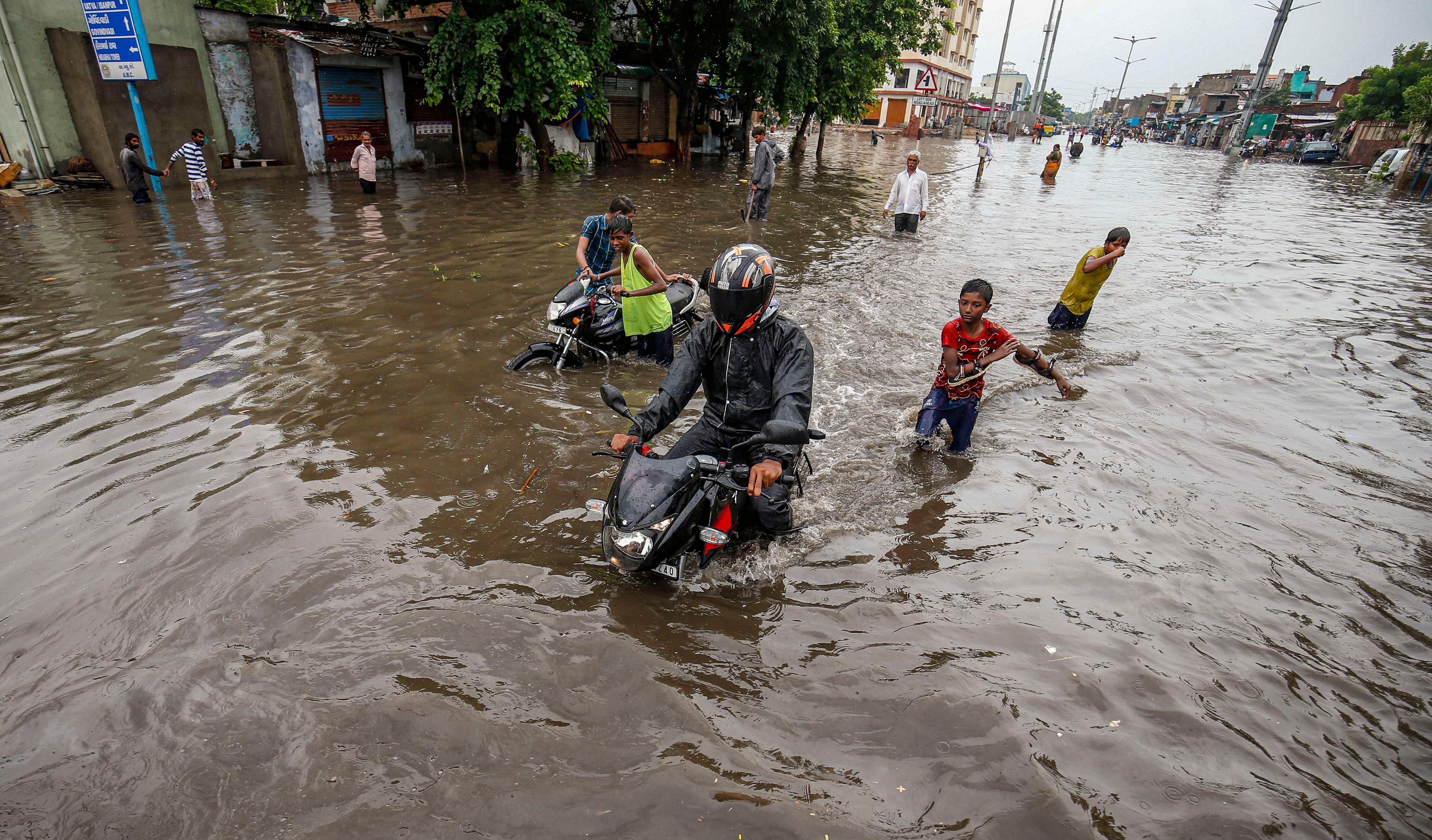 People wade across a waterlogged area following heavy monsoon rainfall. Credits: PTI Photo