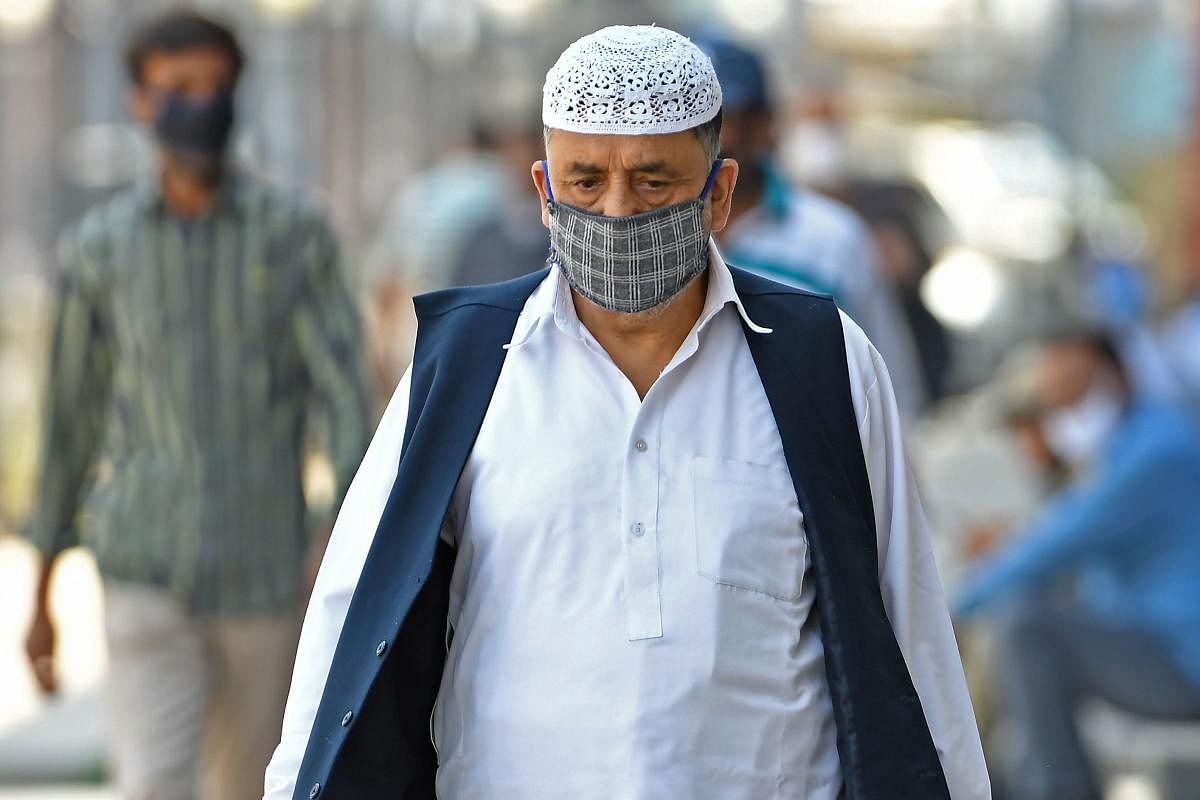 People wearing facemasks walk along the street during a lockdown imposed by authorities after a sudden surge of Covid-19 coronavirus cases, in Srinagar on July 14, 2020. Credit: AFP Photo