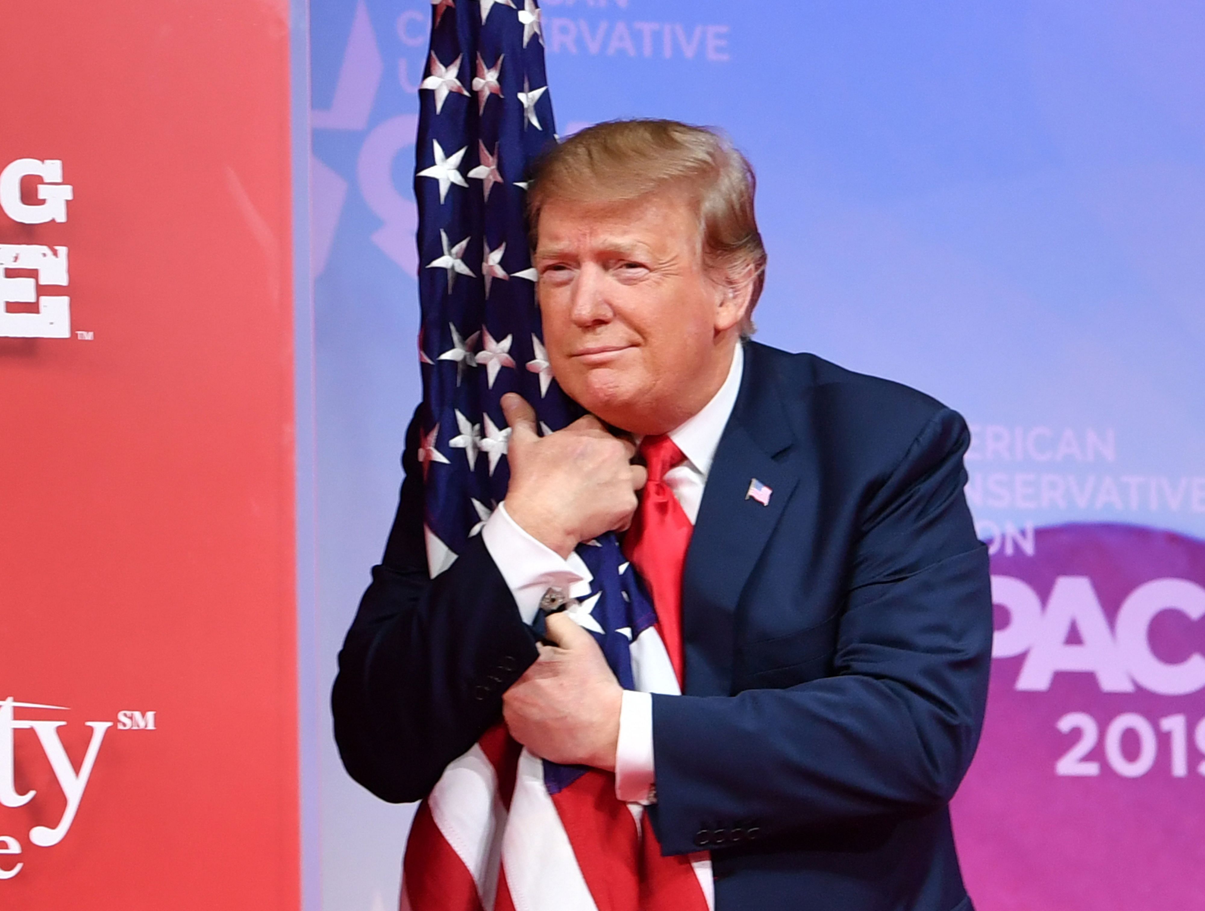 US President Donald Trump hugs the US flag. Credit: AFP File Photo