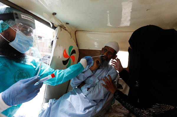 A paramedic wearing protective gear takes a nasal swab sample of a man in rickshaw (tuk tuk), to be tested for the coronavirus disease (Covid-19), in Karachi, Pakistan. Credit: Reuters Photo