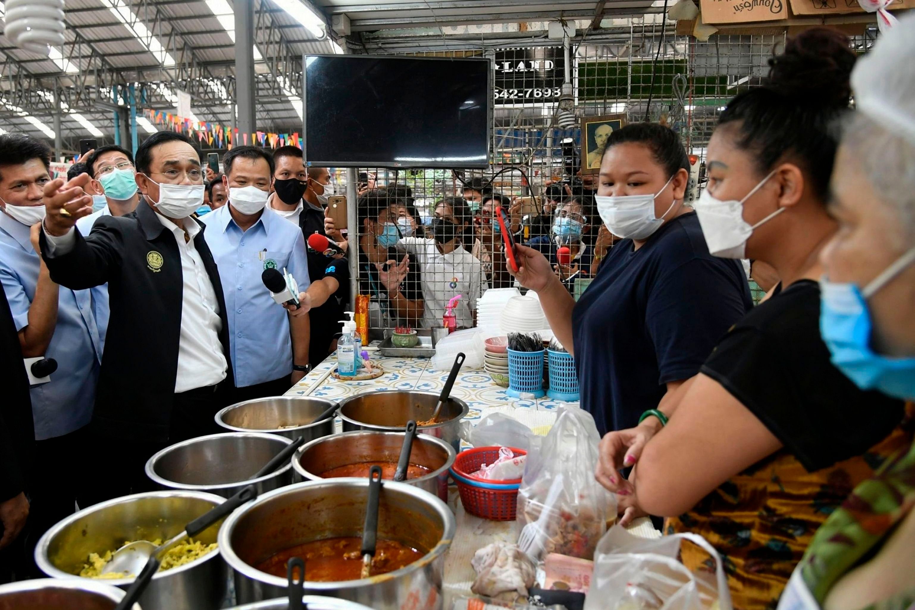 Thailand's Prime Minister Prayut Chan-O-Cha (L) visiting a market in Rayong province to inspect condition following a visit of Egyptian soldier with COVID-19 coronavirus. - Thailand suspended all inbound flights July 14 after an Egyptian soldier skipped self-quarantine and went to a shopping mall in Rayong province before testing positive for COVID-19. Prayut said he took "all responsibility" for the oversight and issued a rare apology for undermining the public's "confidence and safety". Credit: ROYAL THAI GOVERNMENT / AFP