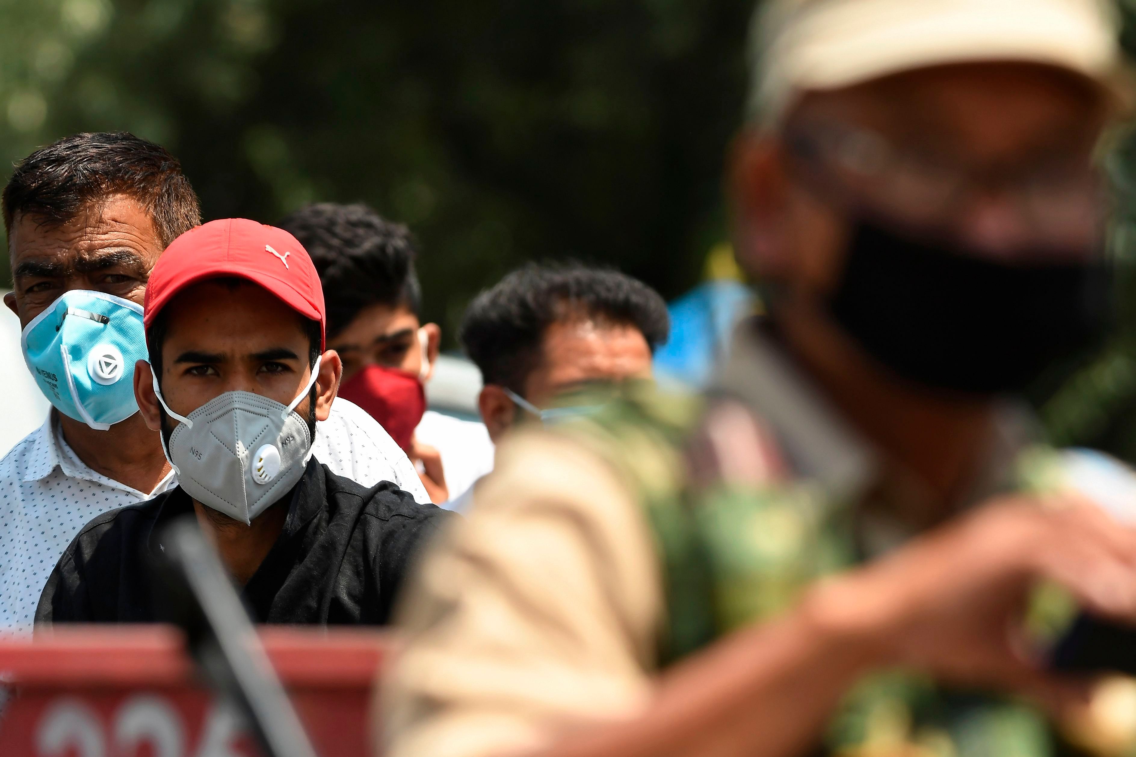 People wearing facemasks watch after a road was blocked by Indian paramilitary troopers during a lockdown imposed by authorities after a sudden surge of Covid-19 coronavirus cases. Credits: AFP Photo