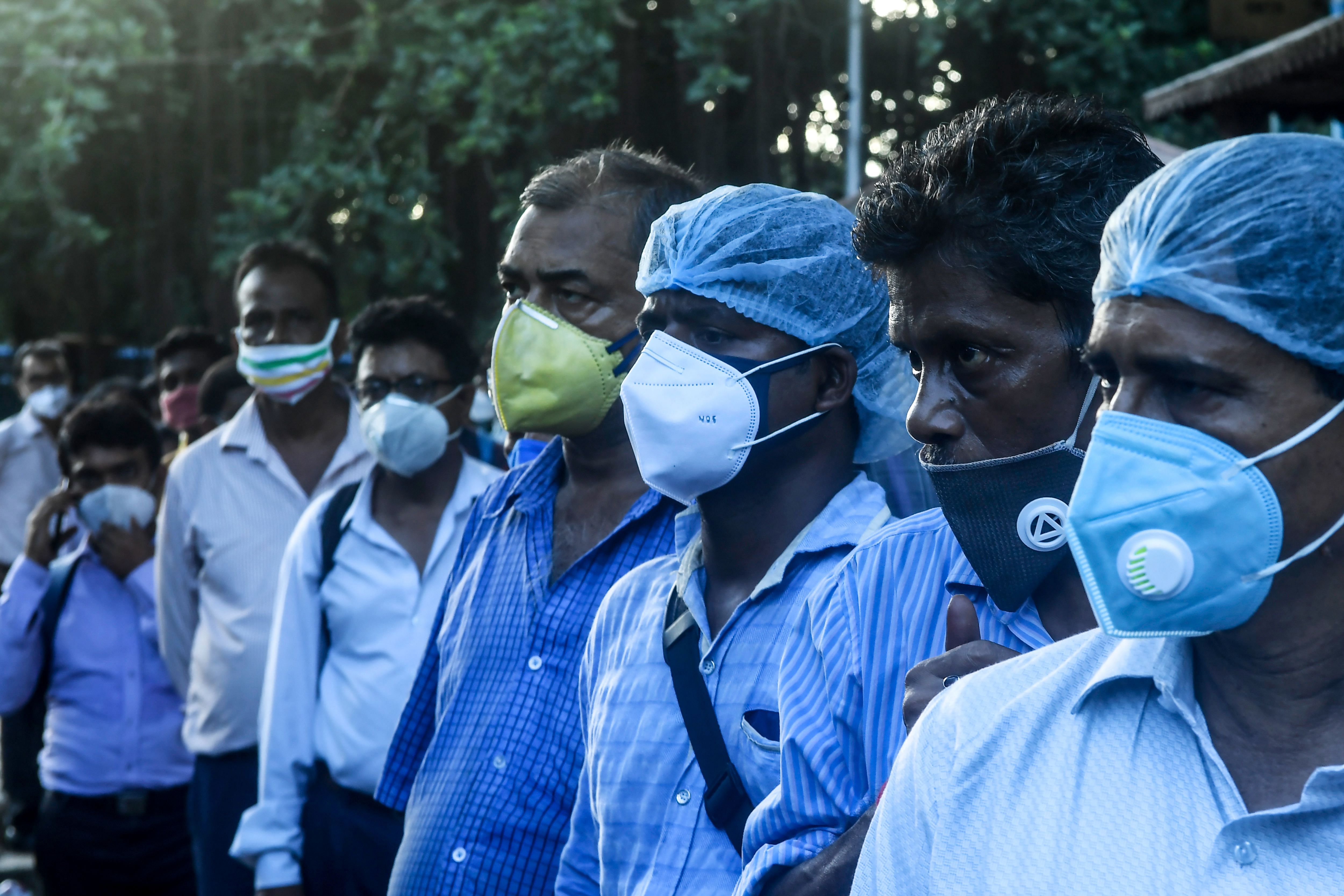 Commuters wearing facemasks wait in a queue to catch a bus to return home after a new lockdown has been implemented as a preventive measure against the Covid-19 coronavirus in Kolkata. Credits: PTI Photo