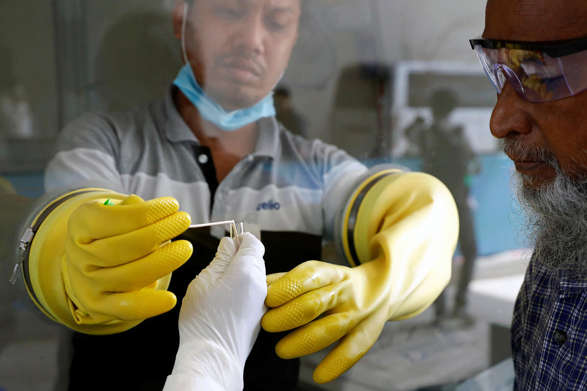 A health worker collects a swab of a man during a coronavirus test in the Mugda Medical College and Hospital as the coronavirus disease (COVID-19) outbreak continues in Dhaka, Bangladesh. Representative image/Credit: Reuters Photo
