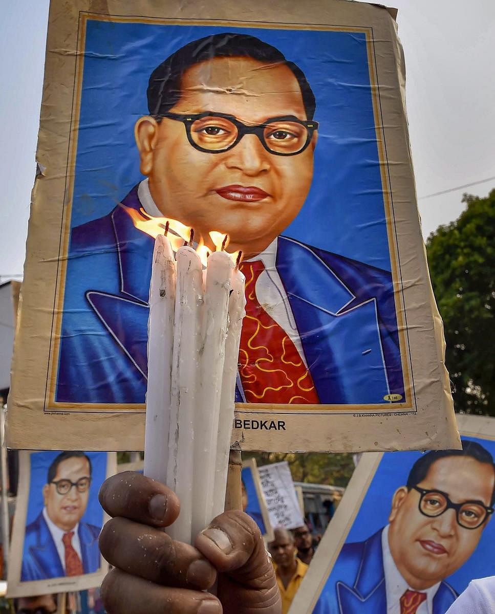 Kolkata: A poster of Dr. BR Ambedkar is seen as Dalit activists participate in a candlelight vigil to protest against Supreme Court's ruling on SC/ST Act, in Kolkata on Wednesday. PTI Photo by Ashok Bhaumik (PTI4_4_2018_000198A)