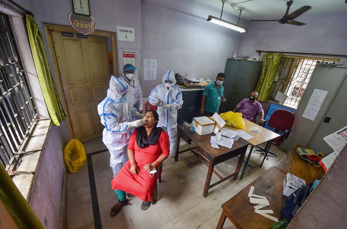 Health workers collect swab sample for Covid-19 test from a woman who was engaged in door-to-door surveillance to detect coronavirus cases, at a health centre, in Kolkata, Tuesday, July 14, 2020. Credit: PTI Photo