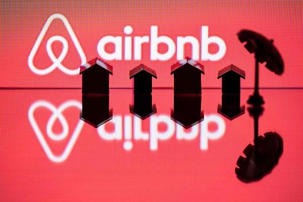 A toy umbella and houses next to the logo of rental website Airbnb. Credit: AFP