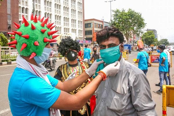 Social activists wearing coronavirus themed helmets offer face masks to people during an awareness campaign against Covid-19 in Madhya Pradesh. Credit: PTI