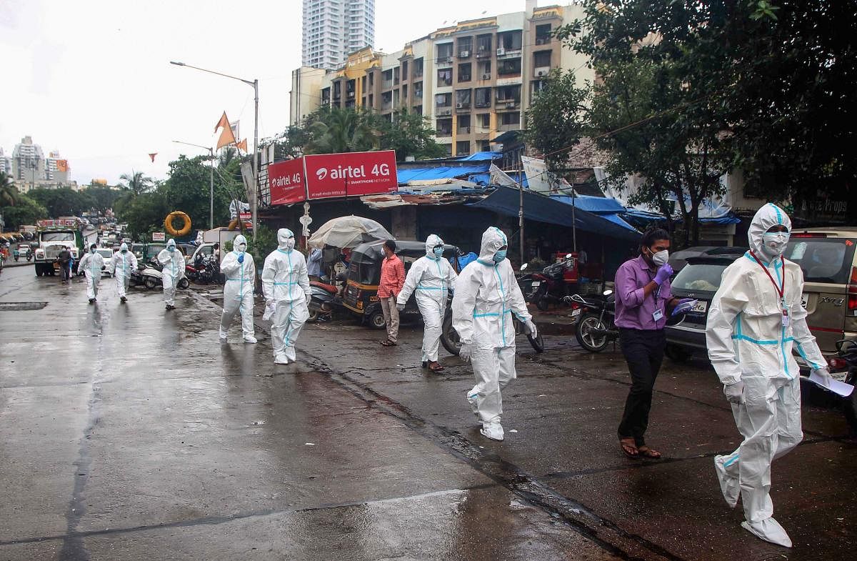 Health workers wearing PPE kits arrive to conduct medical checkup of the residents of Dindoshi area, during Unlock 2.0, at Goregaon in Mumbai. Credit: PTI