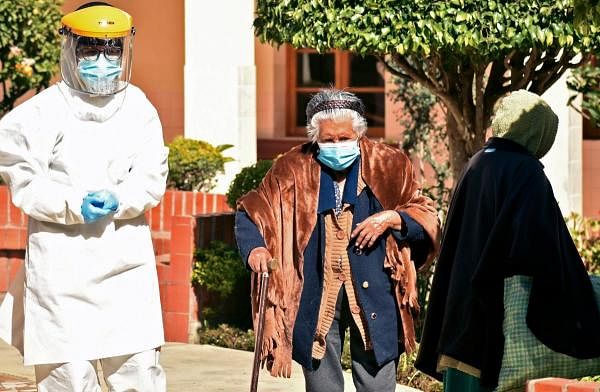 A health worker walks next to an elderly woman to be tested for Covid-19 at the San Jose nursing home in Cochabamba, Bolivia. Credit: AFP Photo