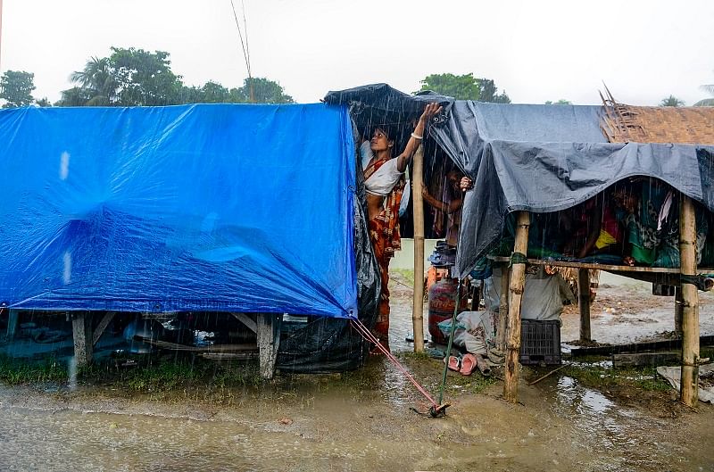  A woman tries to cover her makeshift shelter as it rains, in a flood-hit area of Morigaon. Credits: PTI Photo