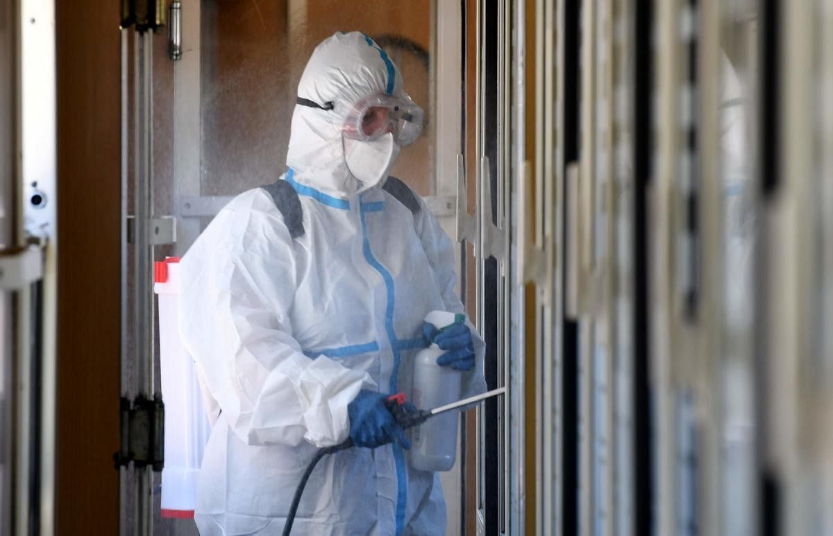 A worker wearing protective gear holds a sanitizer and clean a wagon of the train coming directly from Prague. Credit: AFP