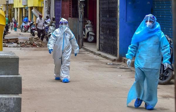  Medics wearing PPE kits arrive to conduct COVID-19 Rapid Antigen test at Kalasipalyam during a week lockdown imposed due to surge in coronavirus cases, in Bengaluru. Credit: PTI Photo