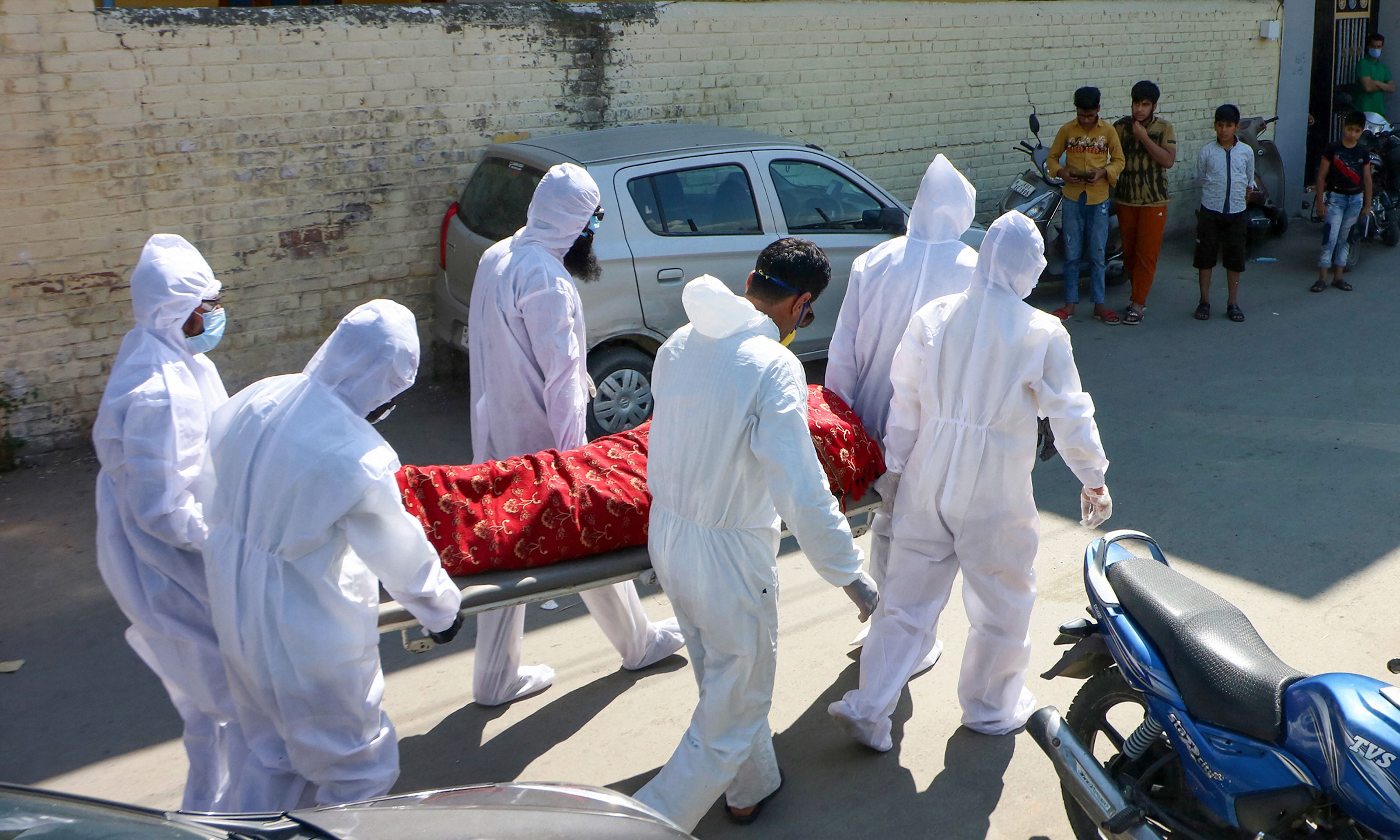 Healthcare workers and family members wearing PPE kits carry the body of a 70-year-old man, who died due to Covid-19, for burial at Narwarah Eidgah in Srinagar. Credits: PTI Photo