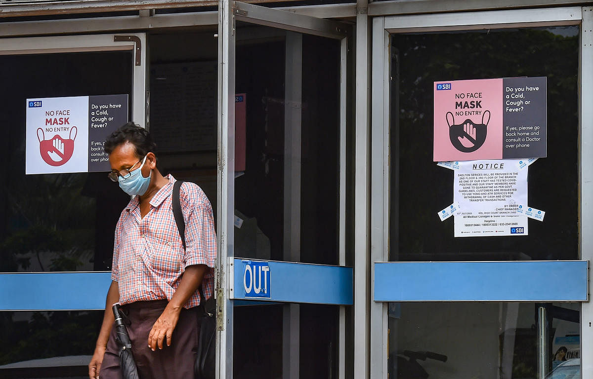 A customer wearing protective mask comes out of the Samriddhi Bhawan, the local head-office of the State Bank of India, in Kolkata, Tuessday, July 7, 2020. (PTI)