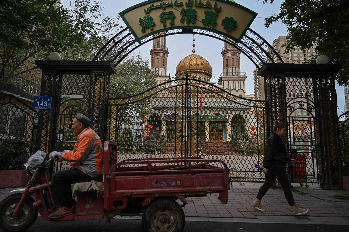 This photo taken on September 11, 2019 shows people walking past a mosque in Urumqi, the regional capital of Xinjiang. Credit: AFP Photo