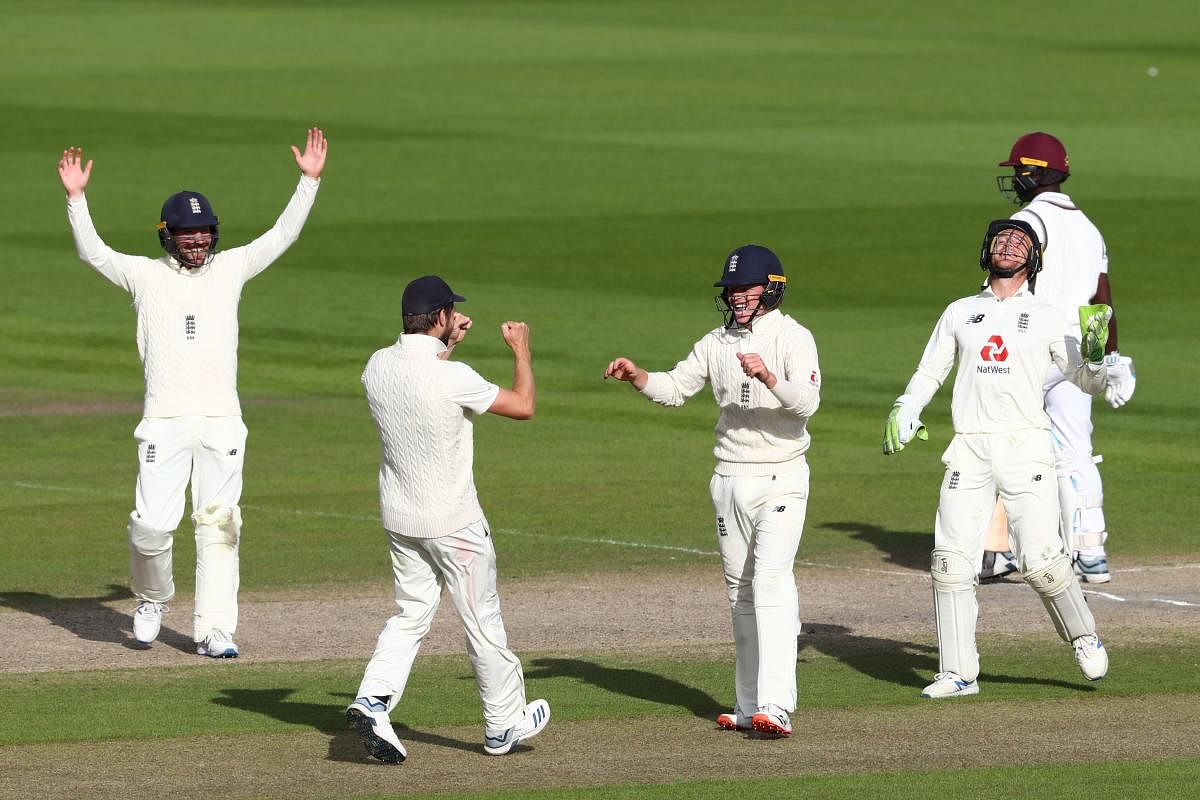 England's Ollie Pope (C) celebrates with teammates after making a catch to dismiss West Indies' Kemar Roach off the bowling of England's Dom Bess, the final wicket as England wrap up the test on the final day of the second Test cricket match between England and the West Indies at Old Trafford in Manchester, northwest England on July 20, 2020. (AFP)