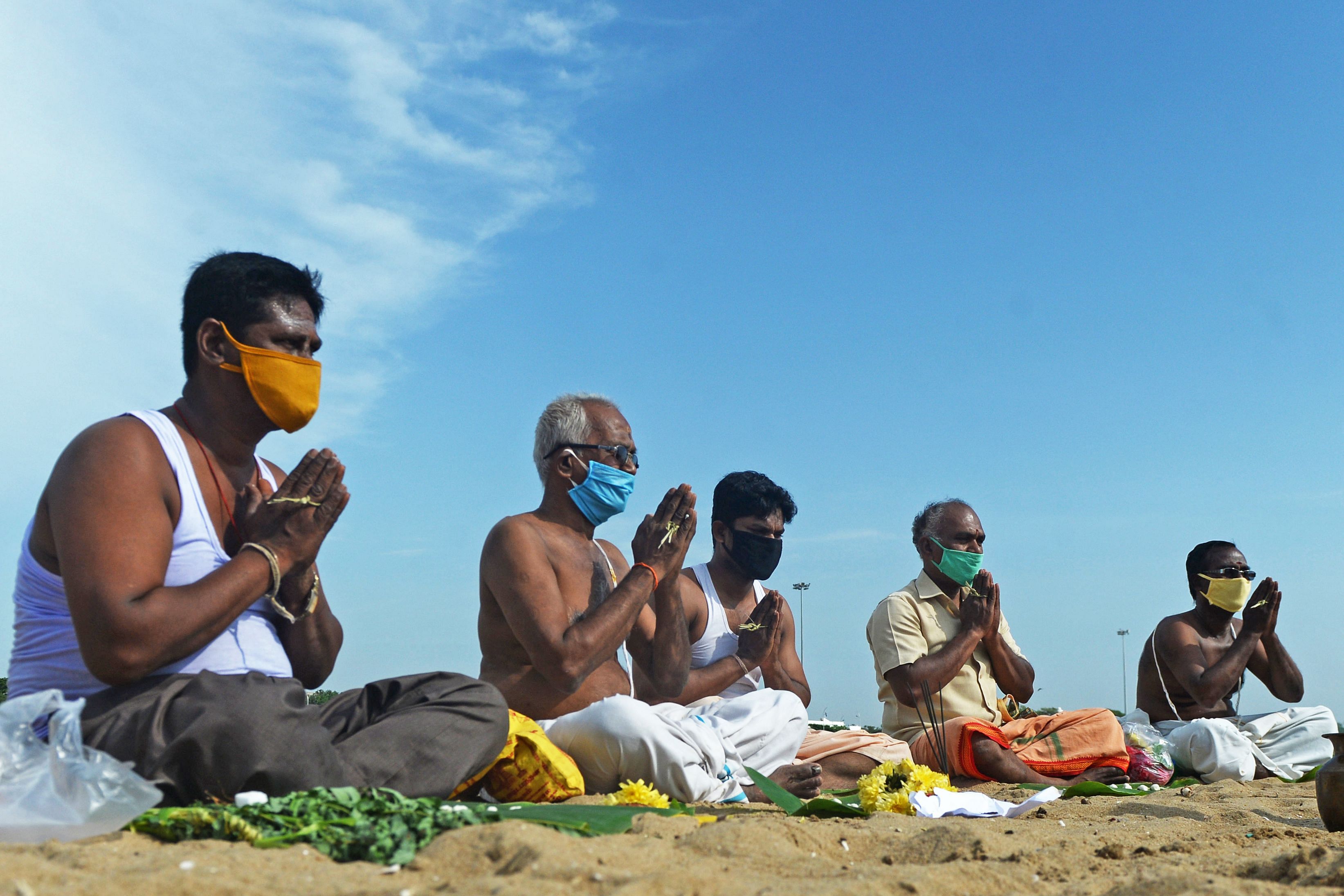 Hindu devotees offer food and prayers as they perform 'Tarpan' rituals that are believed to ensure peace and happiness to the souls of one's ancestors, at Marina beach in Chennai. Credits: AFP Photo