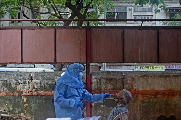 A health worker wearing Personal Protective Equipment (PPE) gear collects a swab sample from a man during medical screening for the COVID-19 coronavirus, at a residential area in Mumbai on July 20, 2020. Credit: AFP Photo