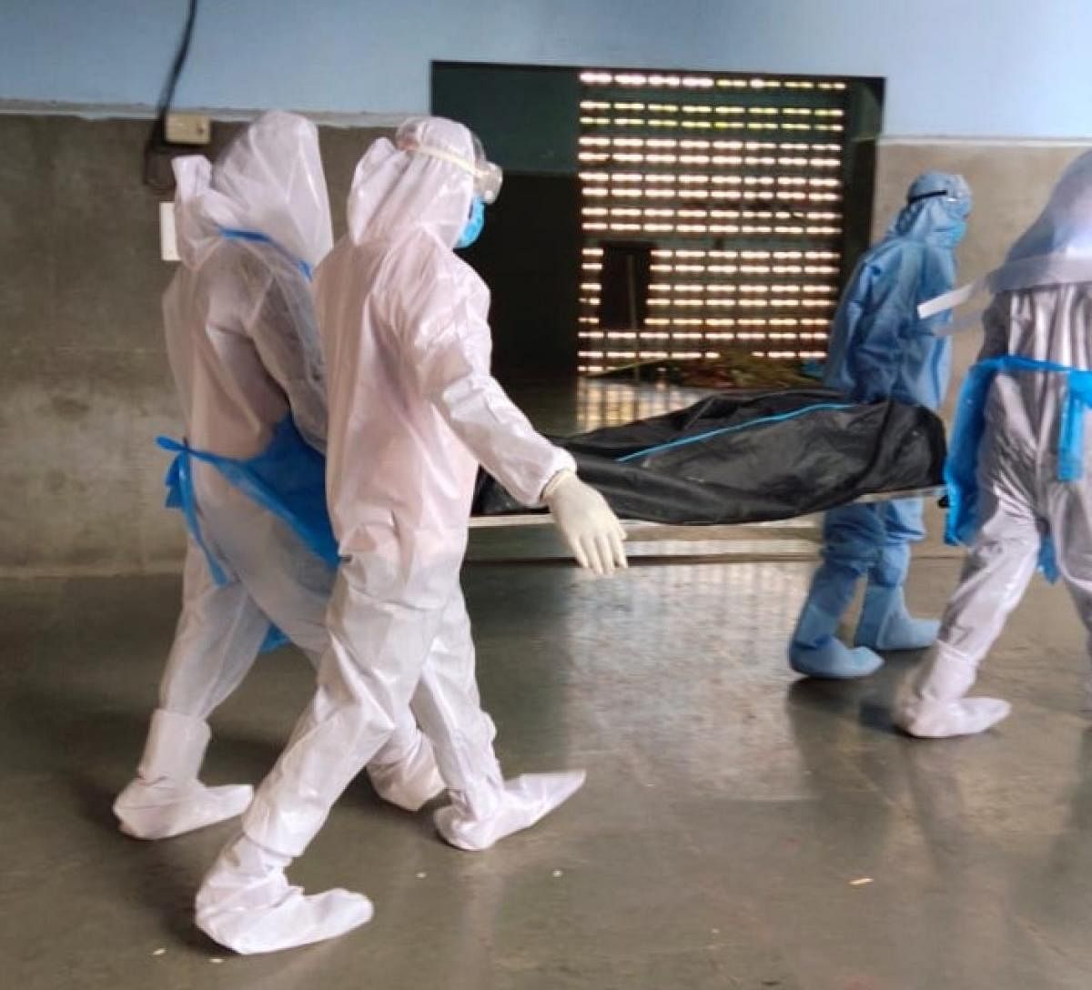 Workers wearing PPE kits take a body at the Sumanahalli electric crematorium. FILE PHOTO