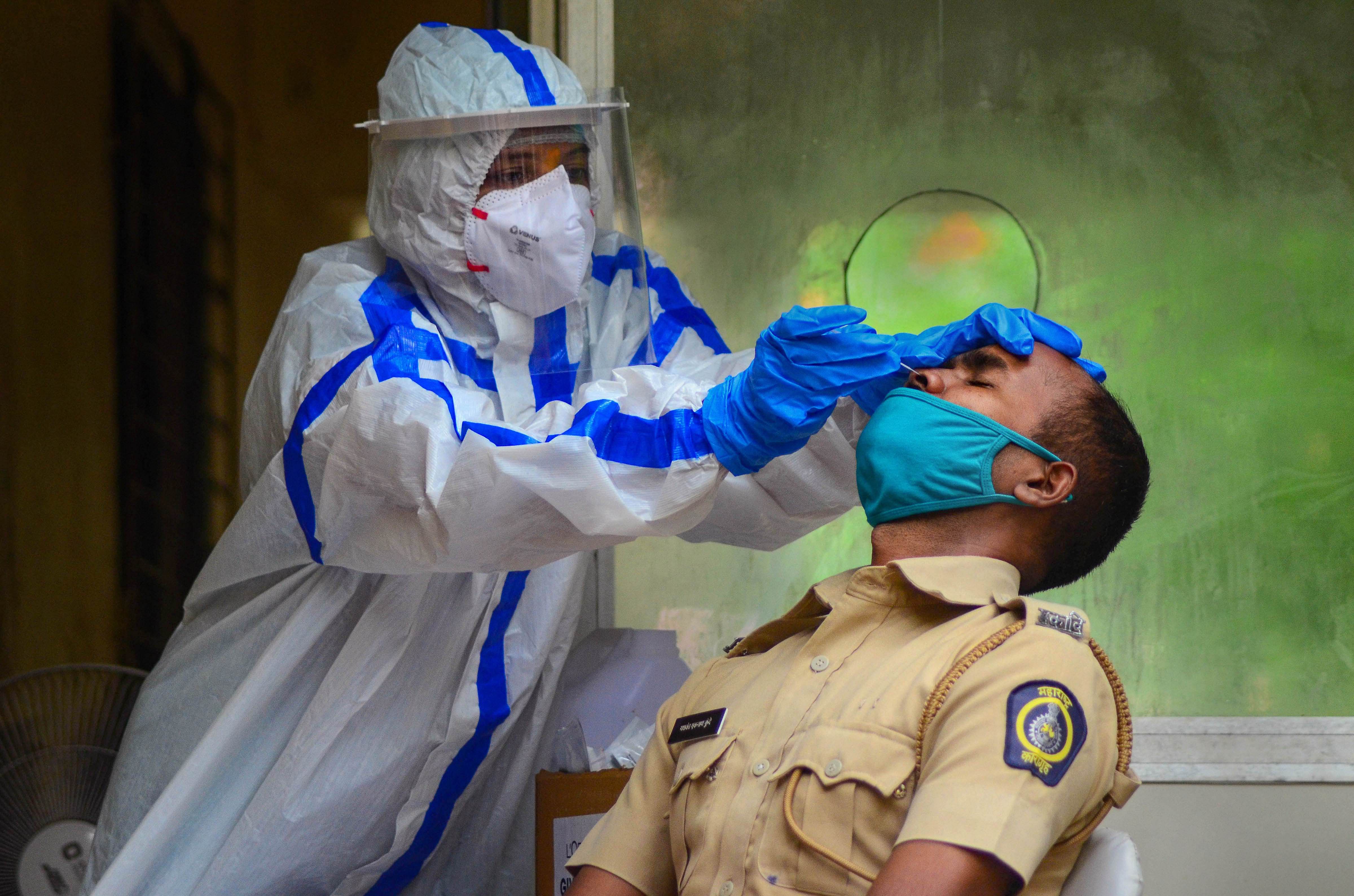 Panvel City Municipal Corporation(PCMC) doctor collects swab sample of a policeman for Rapid Antigen Test at CIDCO Urban Health Centre, in the wake of the Coronavirus. Credits: PTI Photo