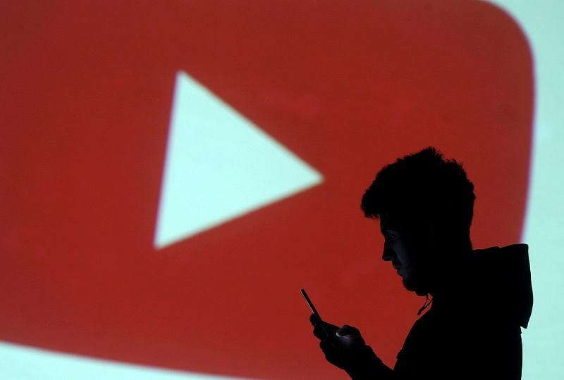  A silhouette of a mobile user is seen next to a screen projection of Youtube logo. Credits: Reuters Photo