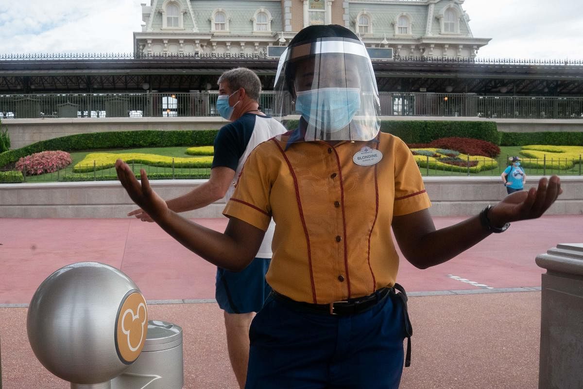 An employee at Walt Disney World Resort's Magic Kingdom wears a facemask and face shield at the entrance to the park during the Covid-19 pandemic. Credit: AFP
