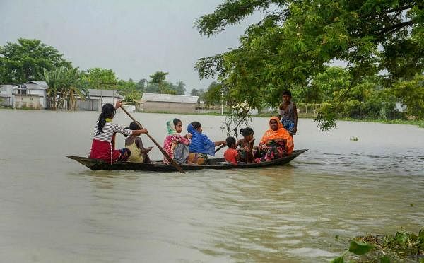 Villagers cross a flooded area on a boat in Morigaon district, Assam. Credit: PTI Photo