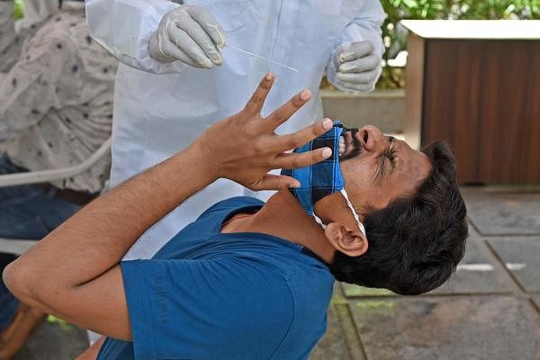 A health worker prepares to take a swab sample from a man as he reacts during a medical screening for the coronavirus, in Ahmedabad. Credit: AFP